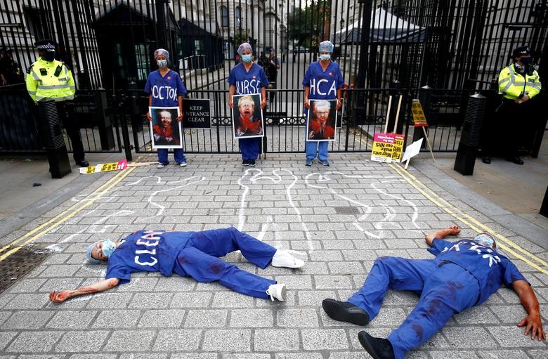 NHS staff members lie on the ground as others hold images depicting Britain's Secretary of State for Health Matt Hancock, Britain's Prime Minister Boris Johnson and Britain's Chancellor of the Duchy of Lancaster Michael Gove during a protest asking for a pay rise, amid the spread of the coronavirus disease (COVID-19), outside Downing Street in London. REUTERS/Henry Nicholls